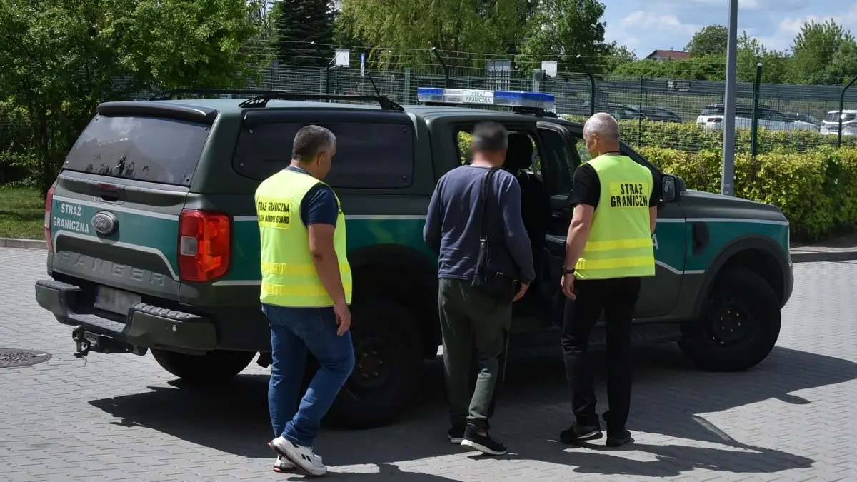 Сотрудники Пограничной службы сопровождают мужчину к служебному автомобилю